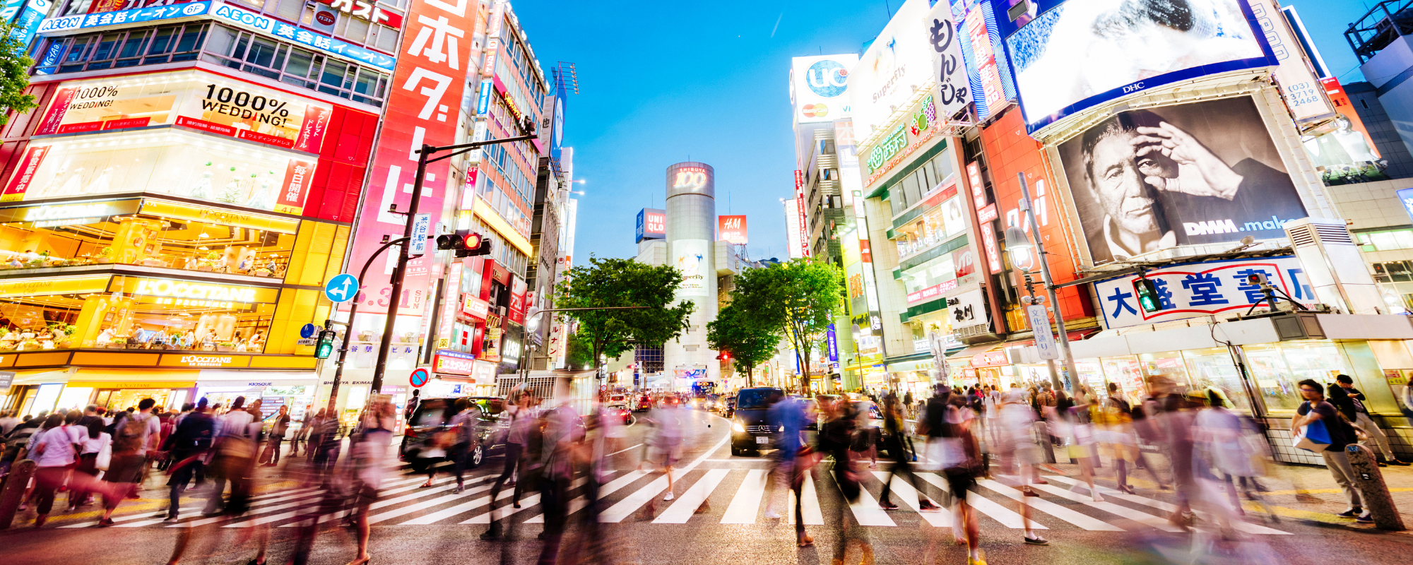 Attraversamento pedonale di Shibuya a Tokyo di sera, tra luci al neon e folla in movimento