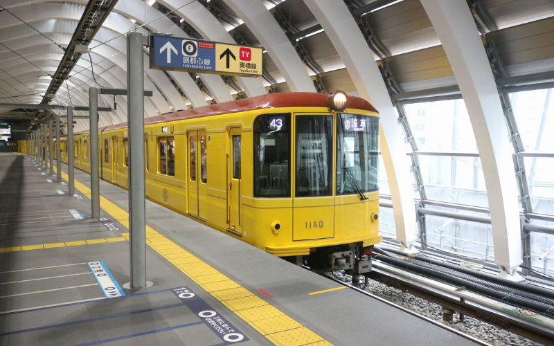 Treno giallo della metropolitana giapponese in arrivo in una stazione moderna a Tokyo